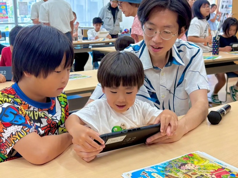 タブレット画面を見ながらゲーム制作に取り組む子どもたちとスタッフ