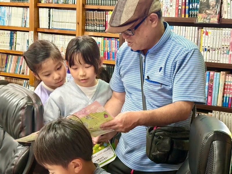 本棚の前で資料を見ながら和泉オーナーの話を聞く子どもたち