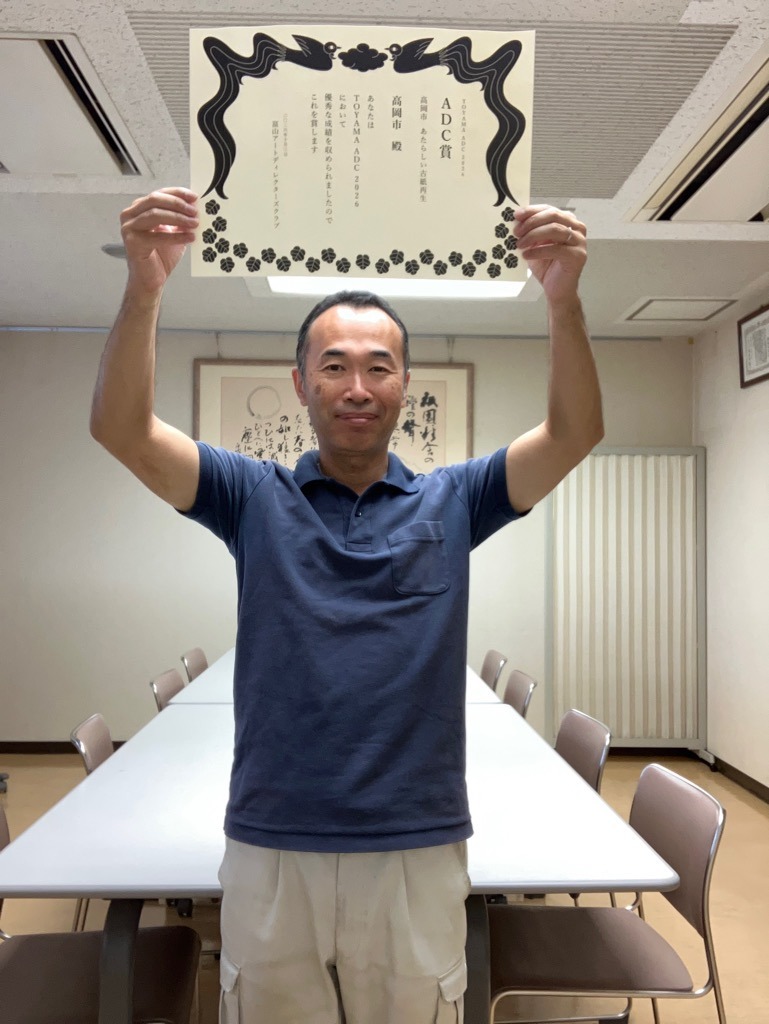 TOYAMA ADC賞 2026の賞状を掲げる高岡市役所環境政策課の鍛冶正博氏
